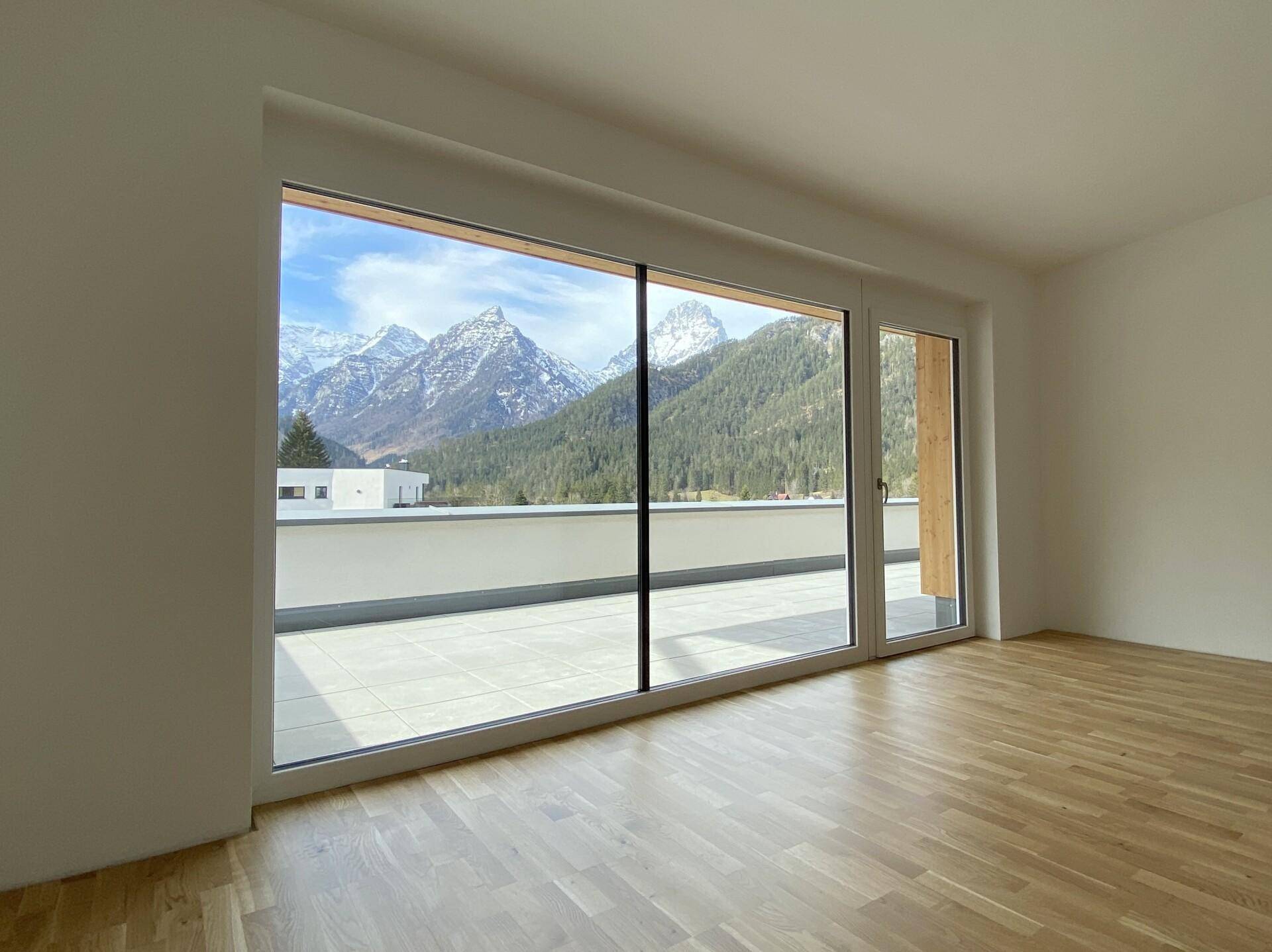 Lichtdurchfluteter Raum mit großen Fenstern, die einen weiten Blick auf die Berge bieten.
