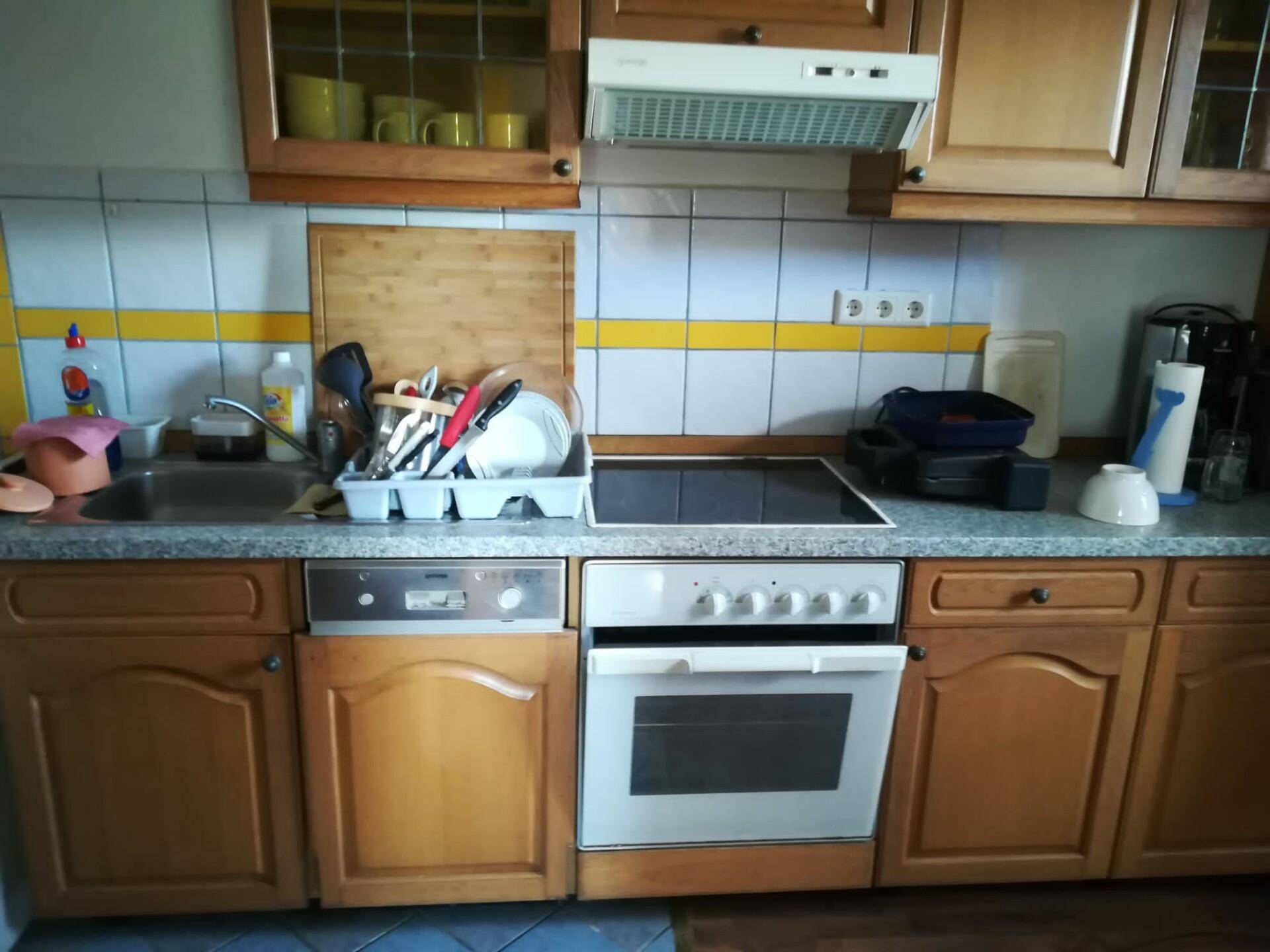 Küche mit Holzschränken, gefliestem Spritzschutz und integrierten Küchengeräten.