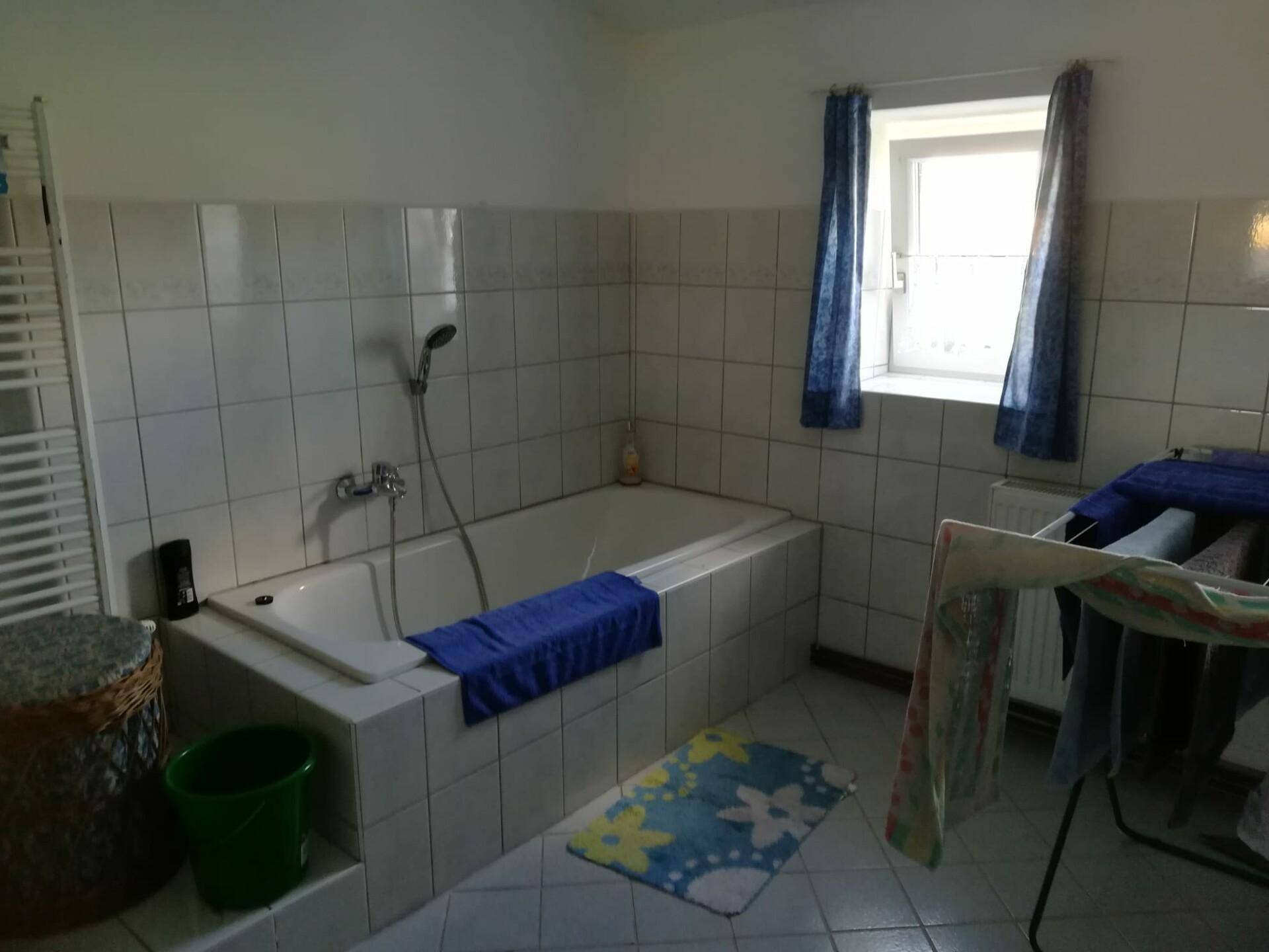 Badezimmer mit Badewanne, Duschfunktion, gefliesten Wänden und Fenster.