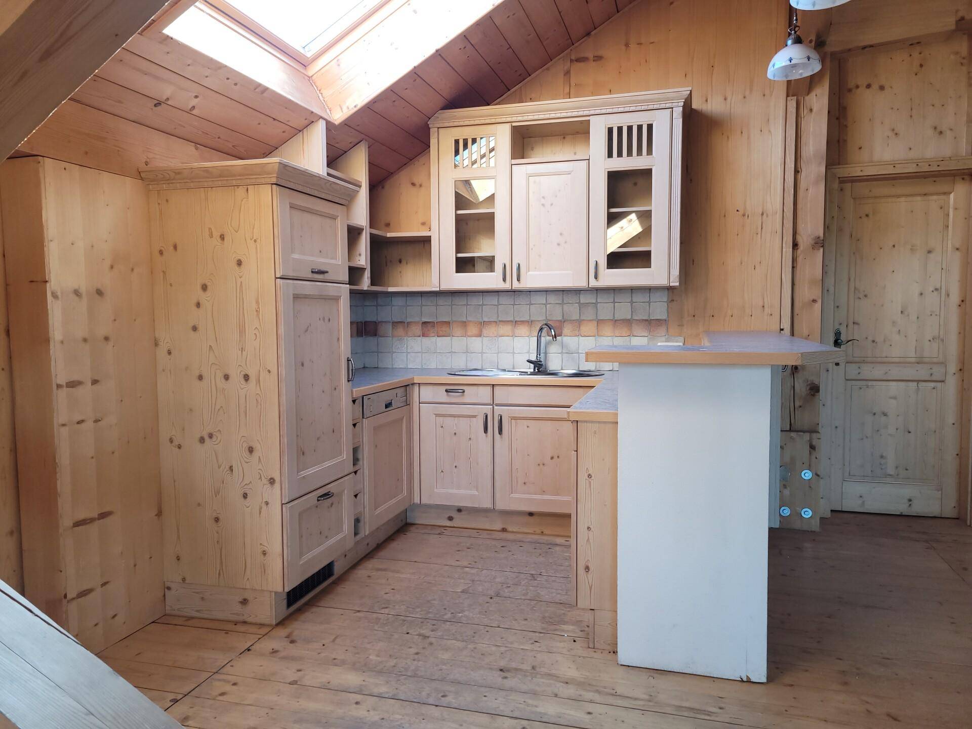 Funktionale Holzküche mit integrierten Schränken, Arbeitsplatte und einem hellen Dachfenster.