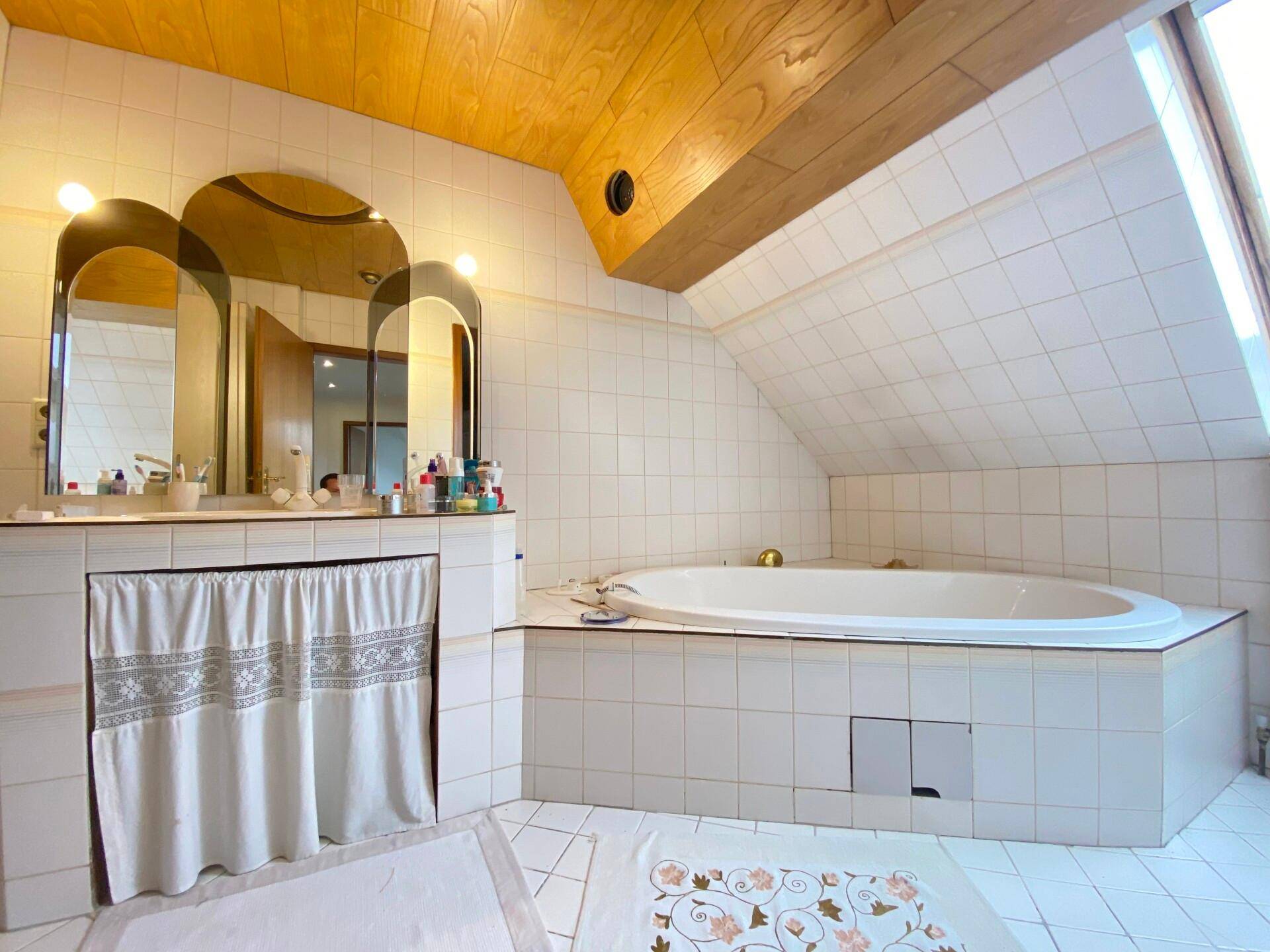 Geräumiges Badezimmer im Dachgeschoss mit großer Badewanne und Dachfenster.