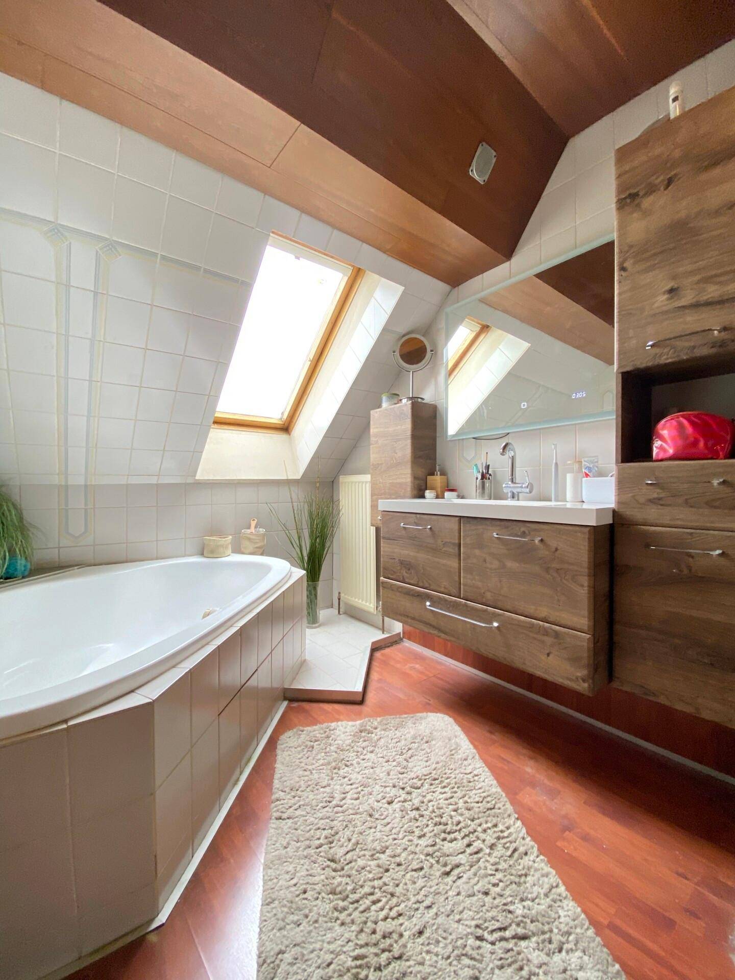 Badezimmer im Dachgeschoss mit Badewanne, Holzdecke und Dachfenster.