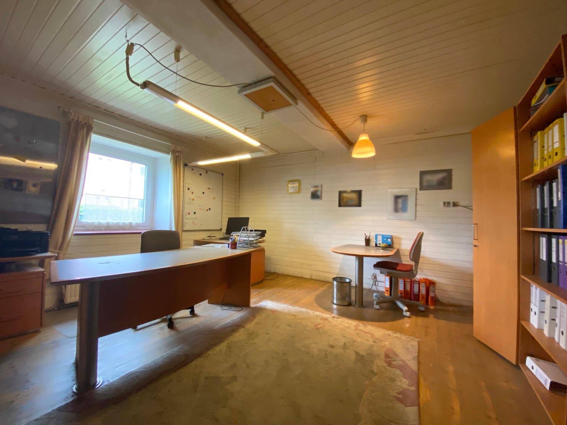 Helles Büro mit Holzpaneelwänden, Schreibtischen und Regalen.