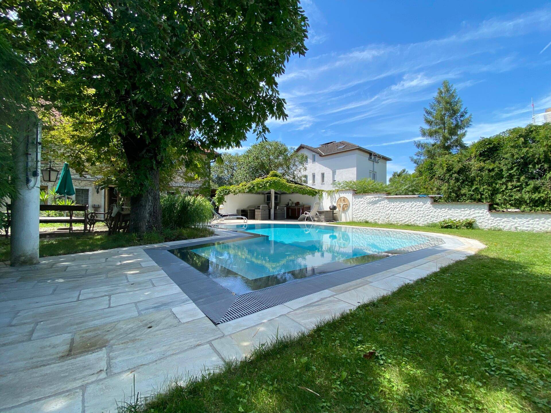 Attraktiver Poolbereich im Garten mit Steinplatten und umgebender Grünfläche.