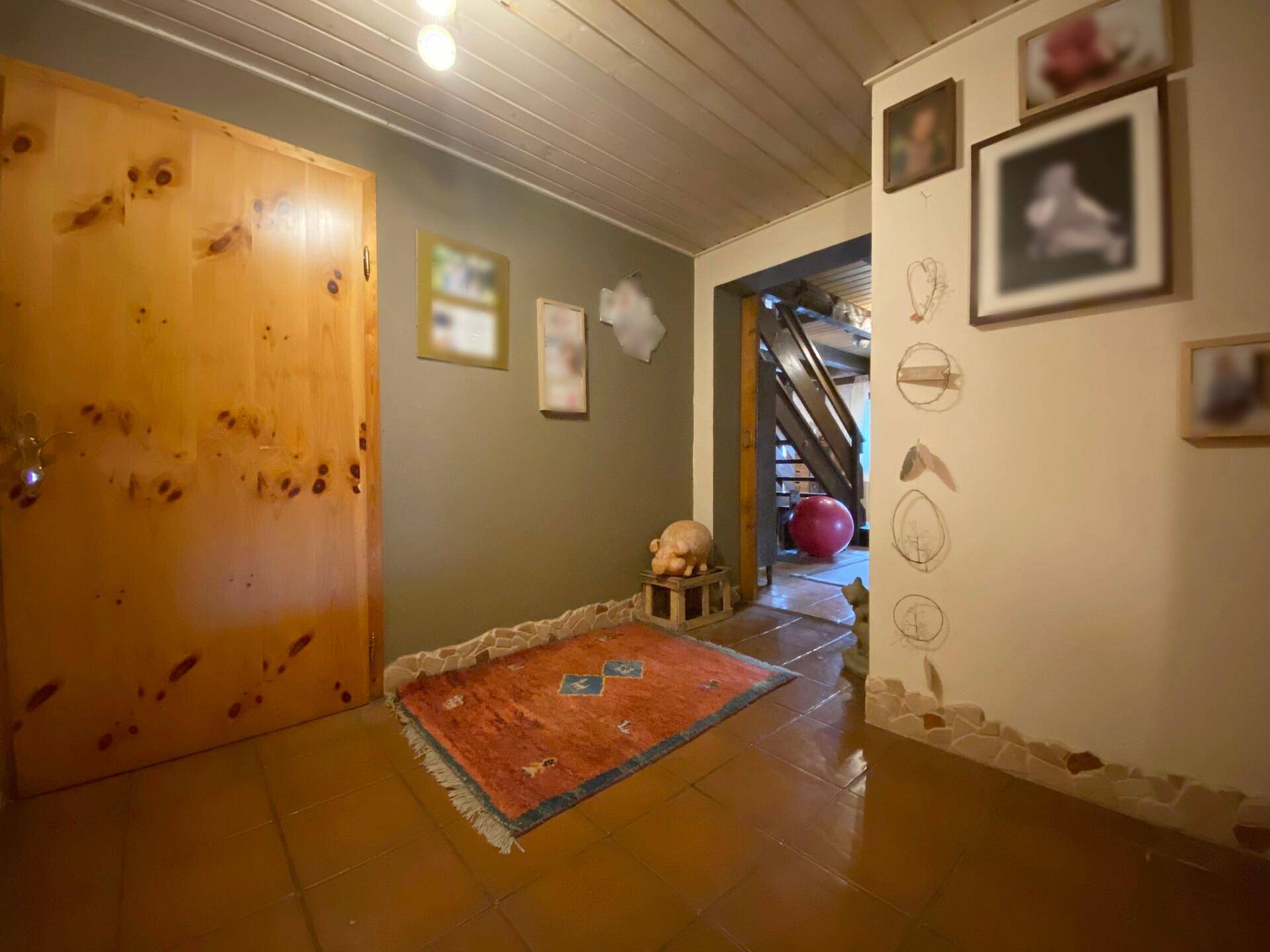 Rustikaler Eingangsbereich mit Holzdecke, Fliesenboden und Treppenaufgang.