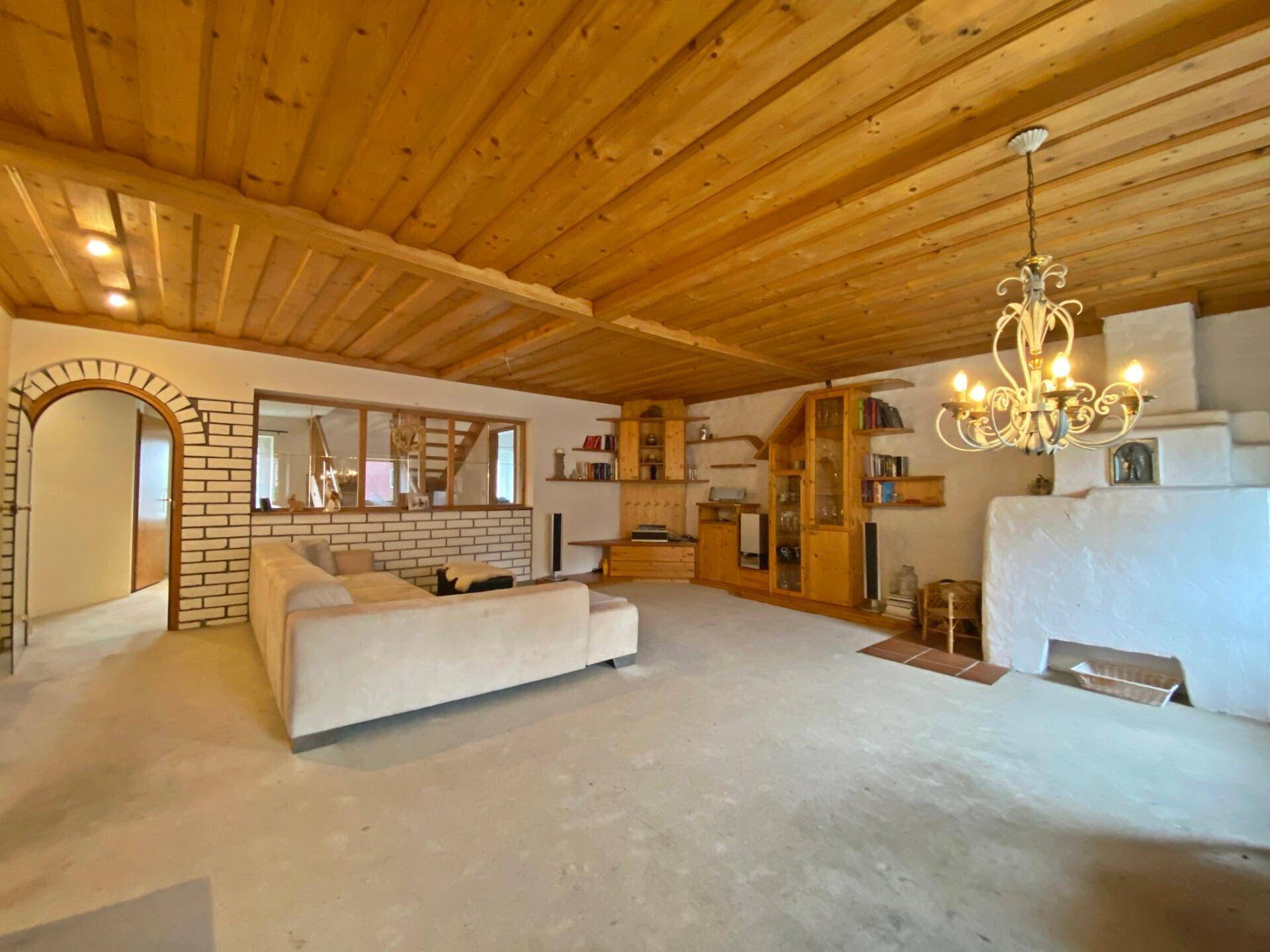 Geräumiges Wohnzimmer mit Holzbalkendecke, Kamin und heller Couch.