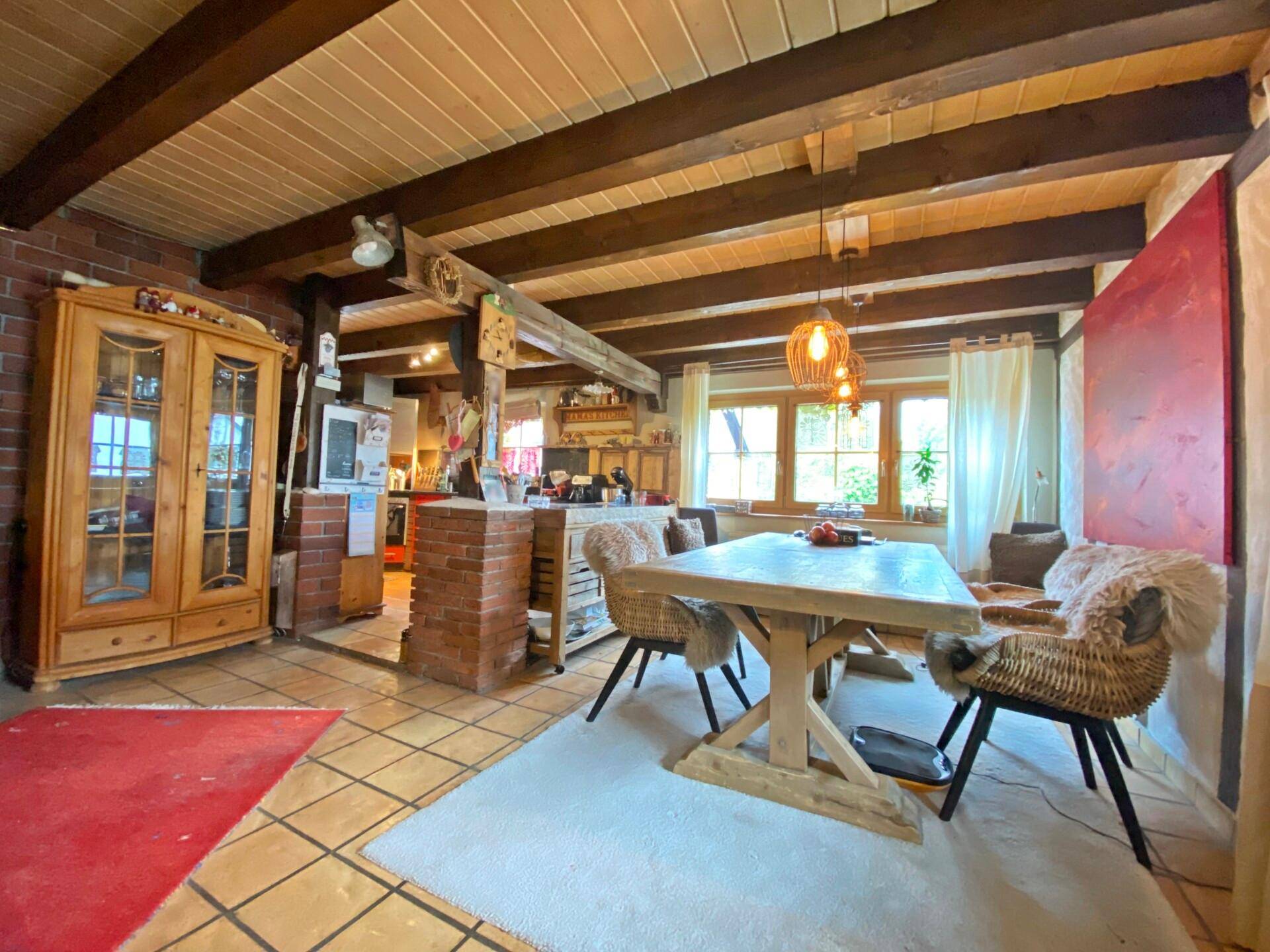 Rustikaler Essbereich mit Holzbalkendecke, Fliesenboden und großem Holztisch.