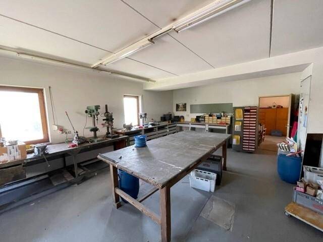 Geräumige Werkstatt mit Arbeitstischen, Werkzeugen und Fenstern für Tageslicht.