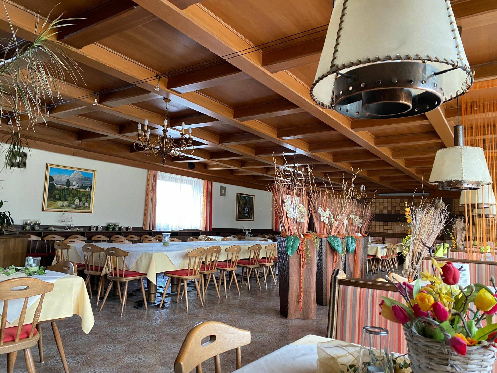 Geräumiger Speisesaal mit Holzbalkendecke, traditioneller Einrichtung und Blick nach draußen.