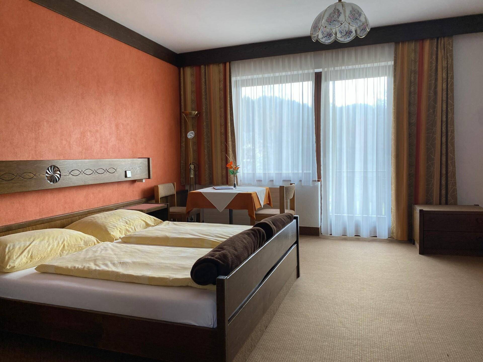 Gemütliches Schlafzimmer mit Doppelbett, Teppichboden und Zugang zu einem Balkon.
