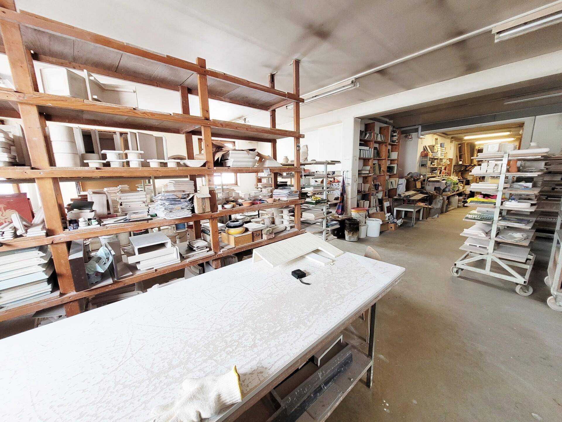 Geräumiger Werkstattbereich mit Holzregalen voller Materialien und Arbeitsflächen.