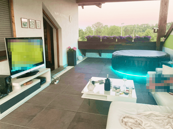 Gemütlicher Balkon mit Whirlpool, Sitzgelegenheiten und Blick ins Grüne.