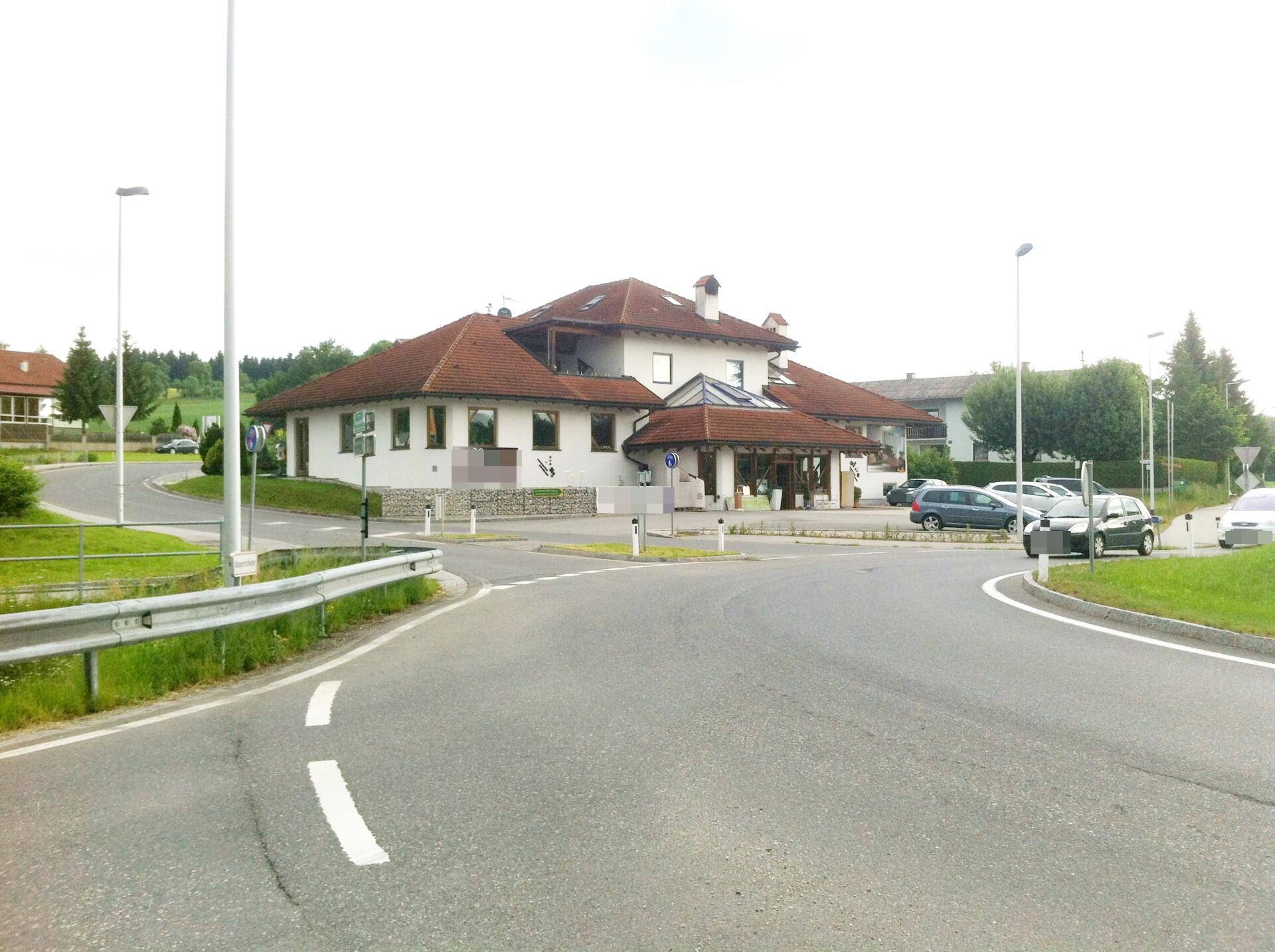 Das Gebäude ist von einer Straße umgeben und bietet Parkmöglichkeiten in einer ländlichen Umgebung.