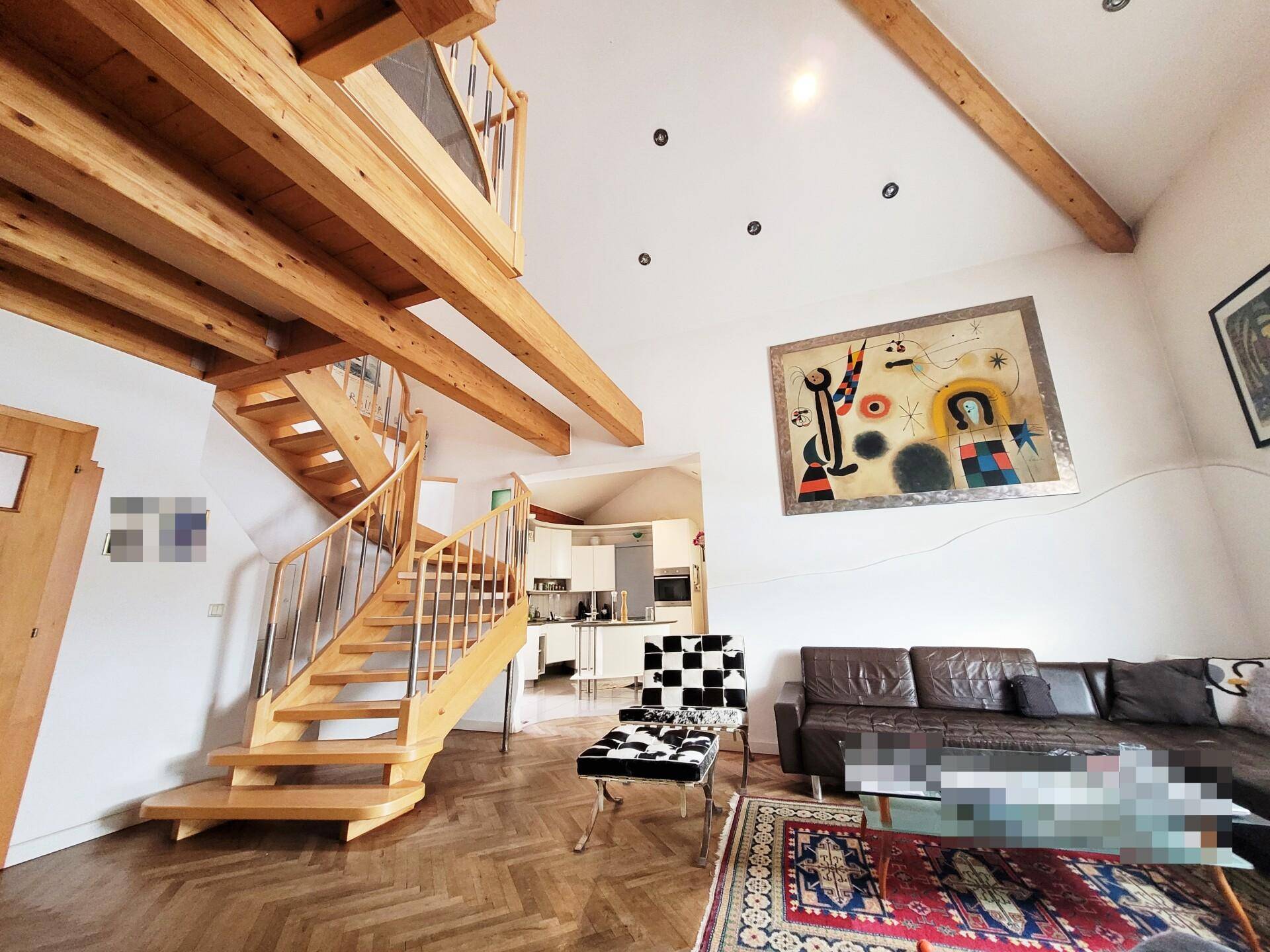 Gemütliches Wohnzimmer mit Holzbalken, Parkettboden und einer eleganten Holztreppe.