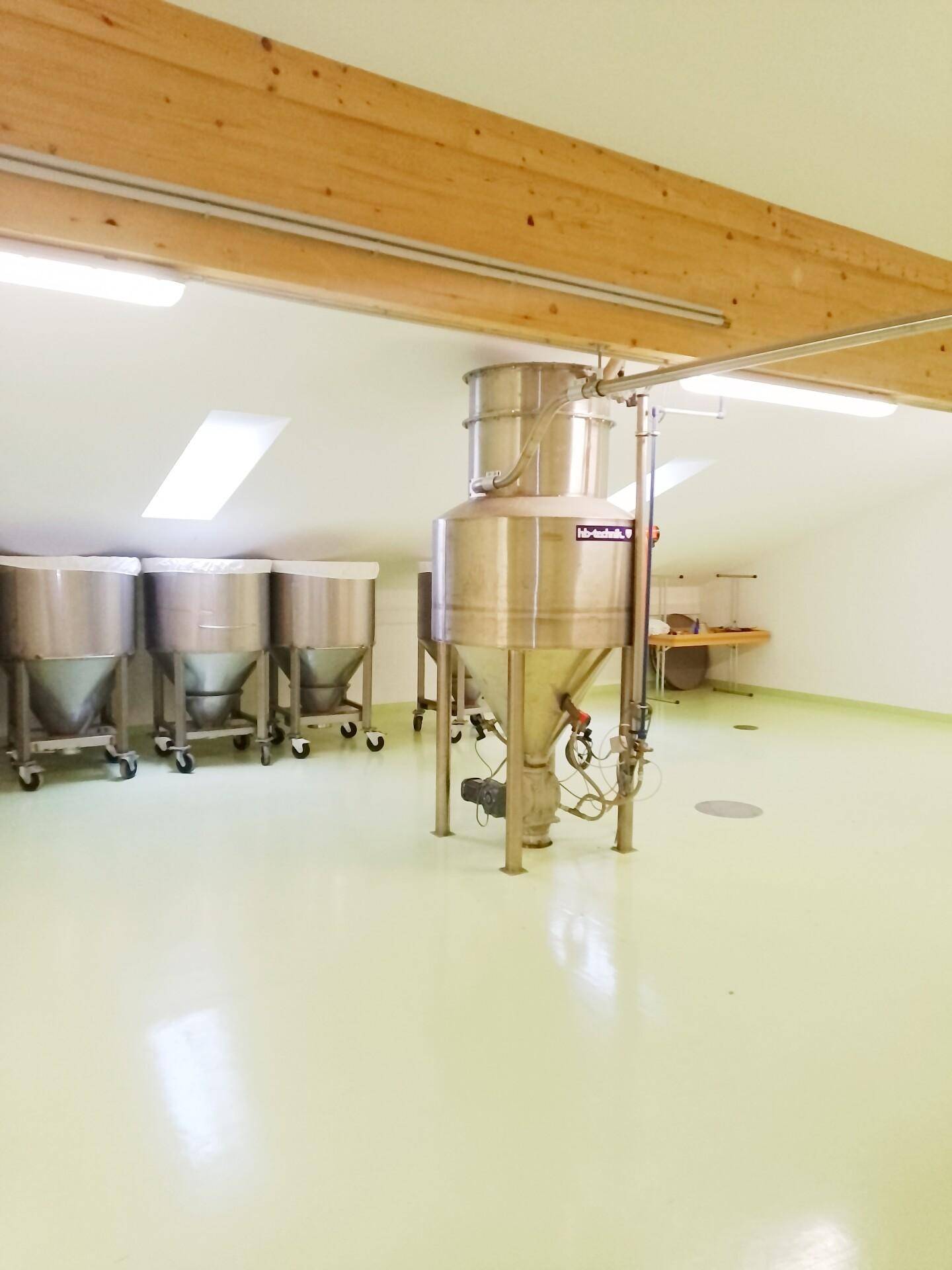 Produktionsbereich im Dachgeschoss mit großen Behältern, schrägen Decken und Dachfenstern.