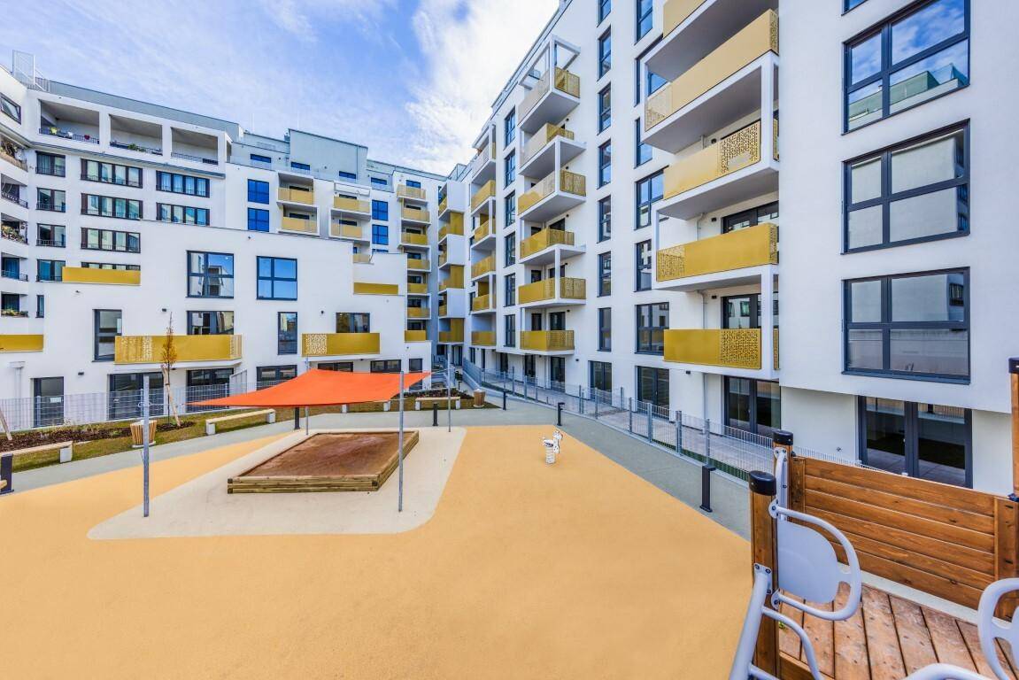 Innenhof des Wohnkomplexes mit Spielplatzbereich und modernen Gebäudefassaden.