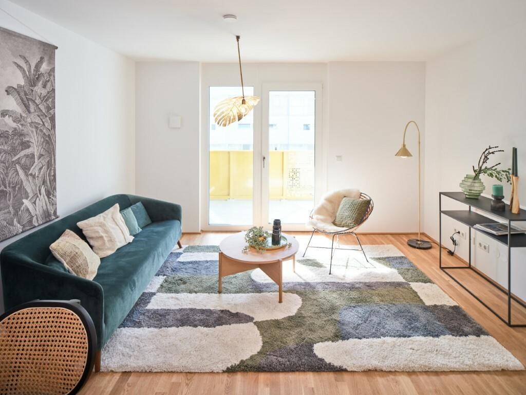 Helles Wohnzimmer mit modernem Teppich, Holzboden und Zugang zu einem Balkon.
