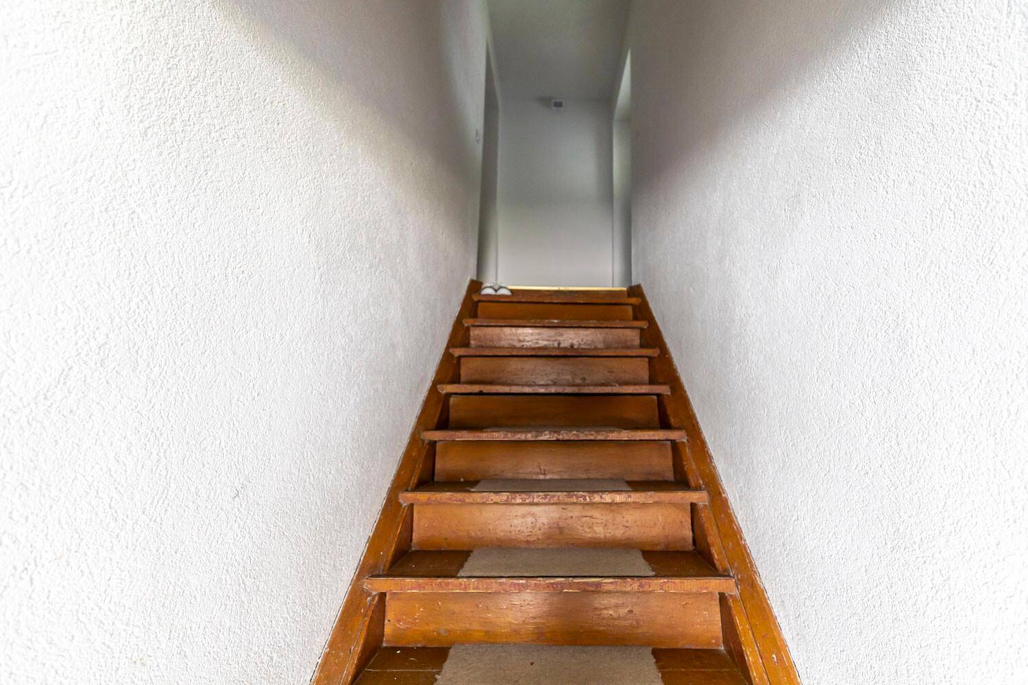 Schmale Holztreppe führt zu einer oberen Etage oder einem Dachbodenbereich.