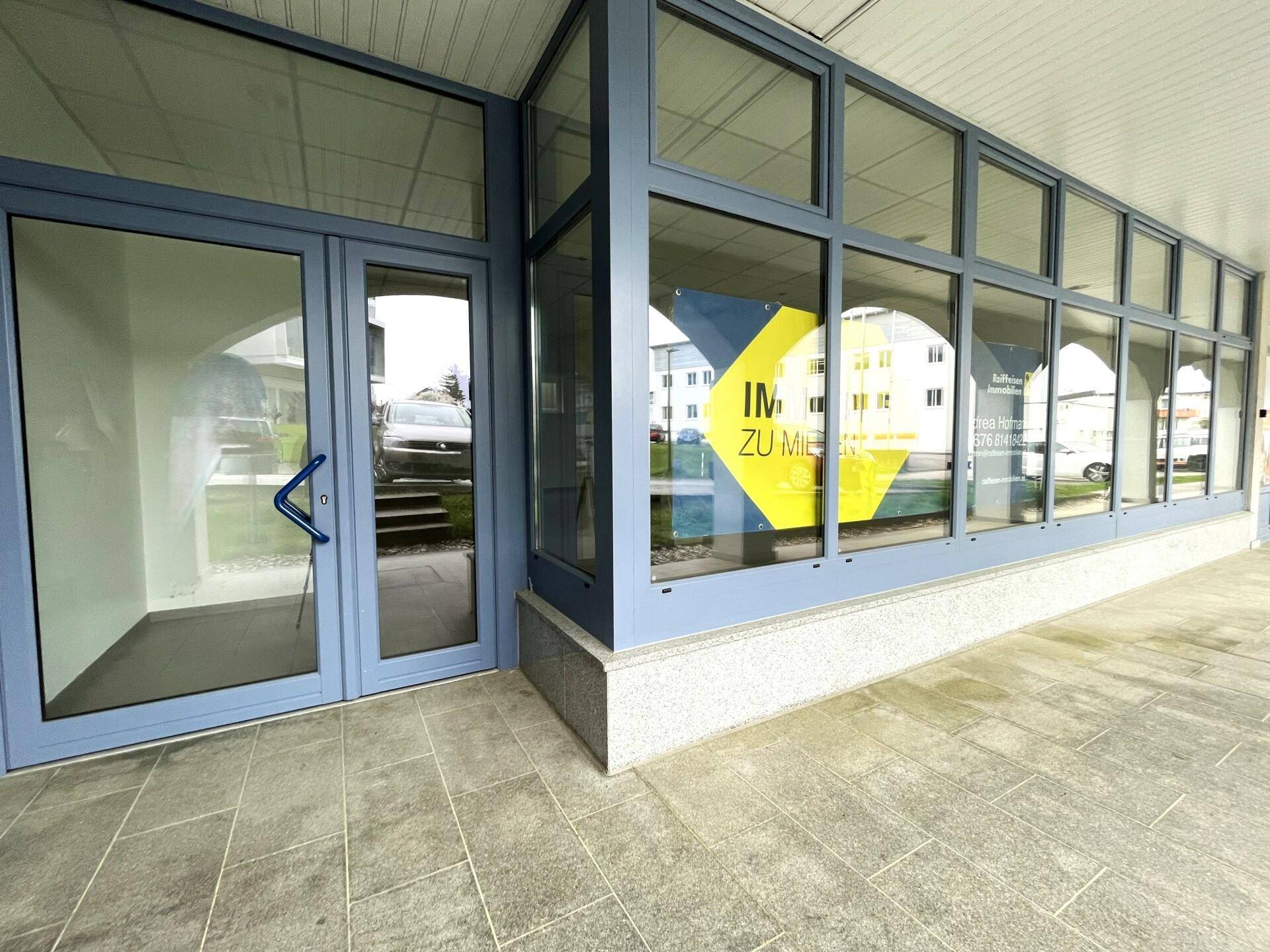 Moderner Eingangsbereich mit großer Glasfassade und Schaufenstern, ideal für Geschäftspräsentationen.