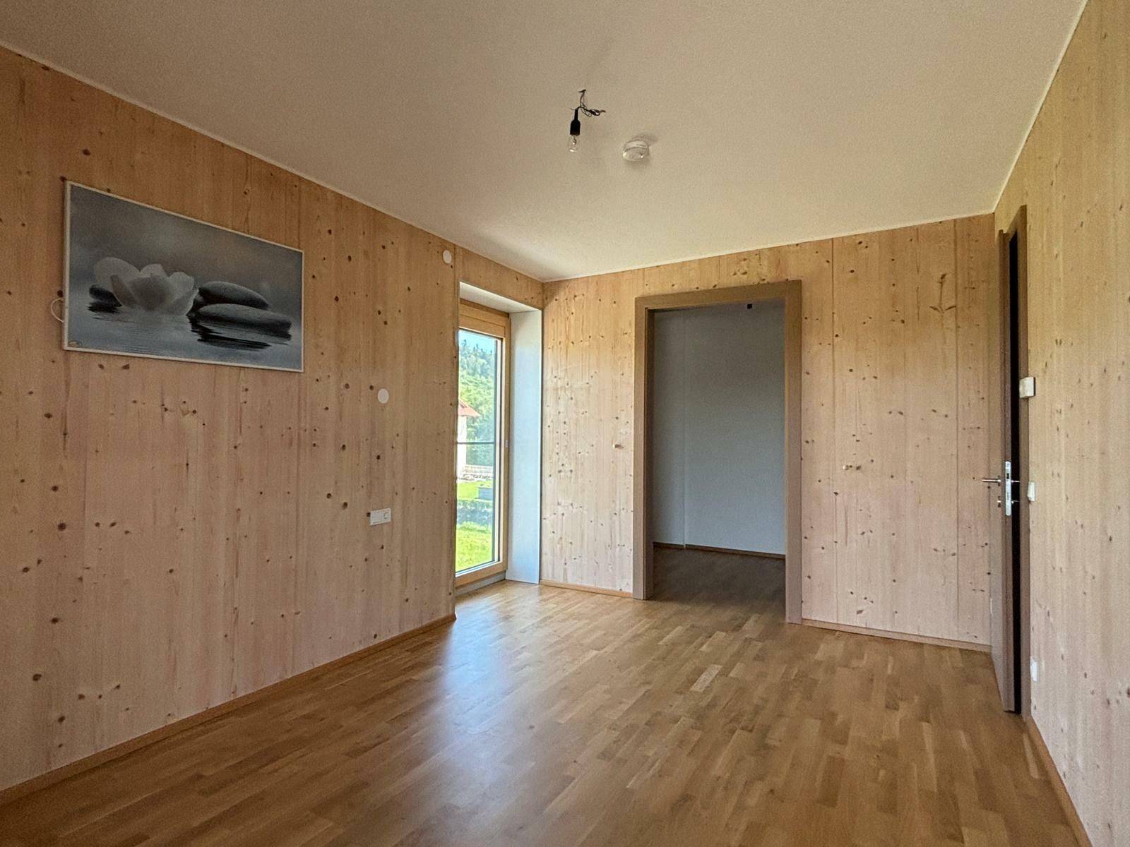 Weiteres Zimmer mit Holzwänden und Parkettboden, bietet flexible Nutzungsmöglichkeiten.