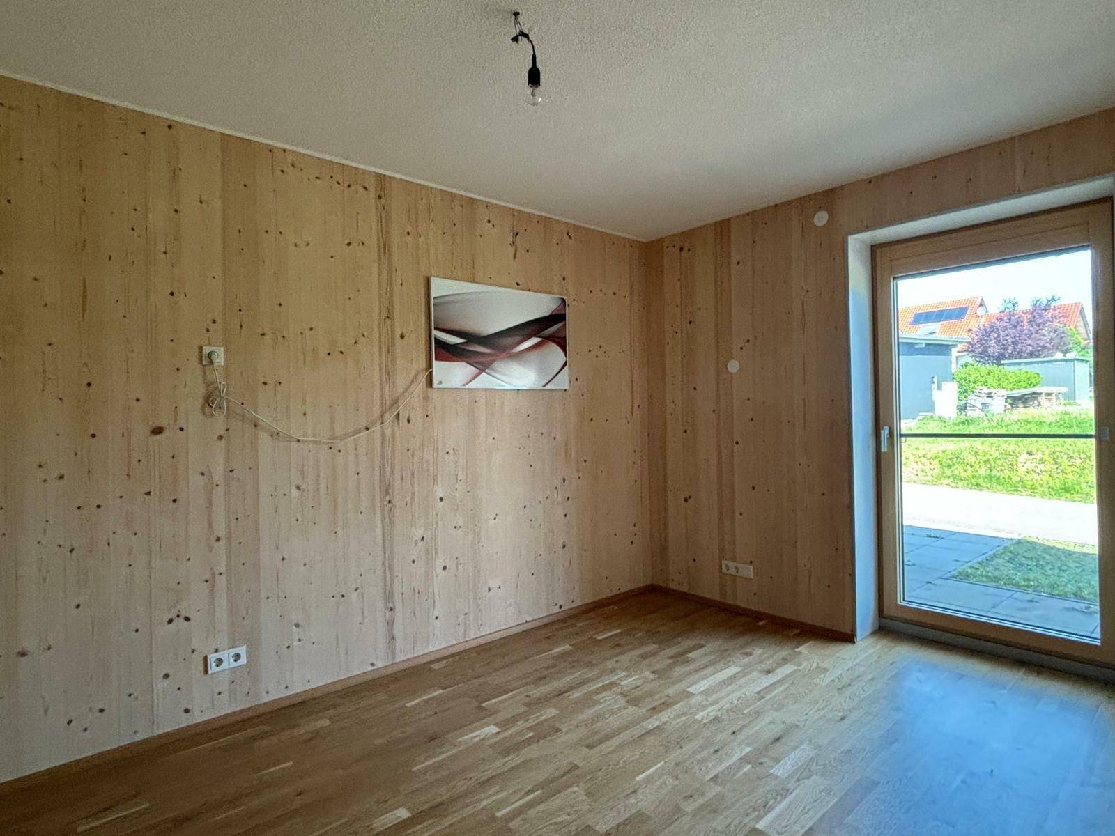 Schlafzimmer mit Holzwänden, Parkettboden und direktem Zugang zum Außenbereich.