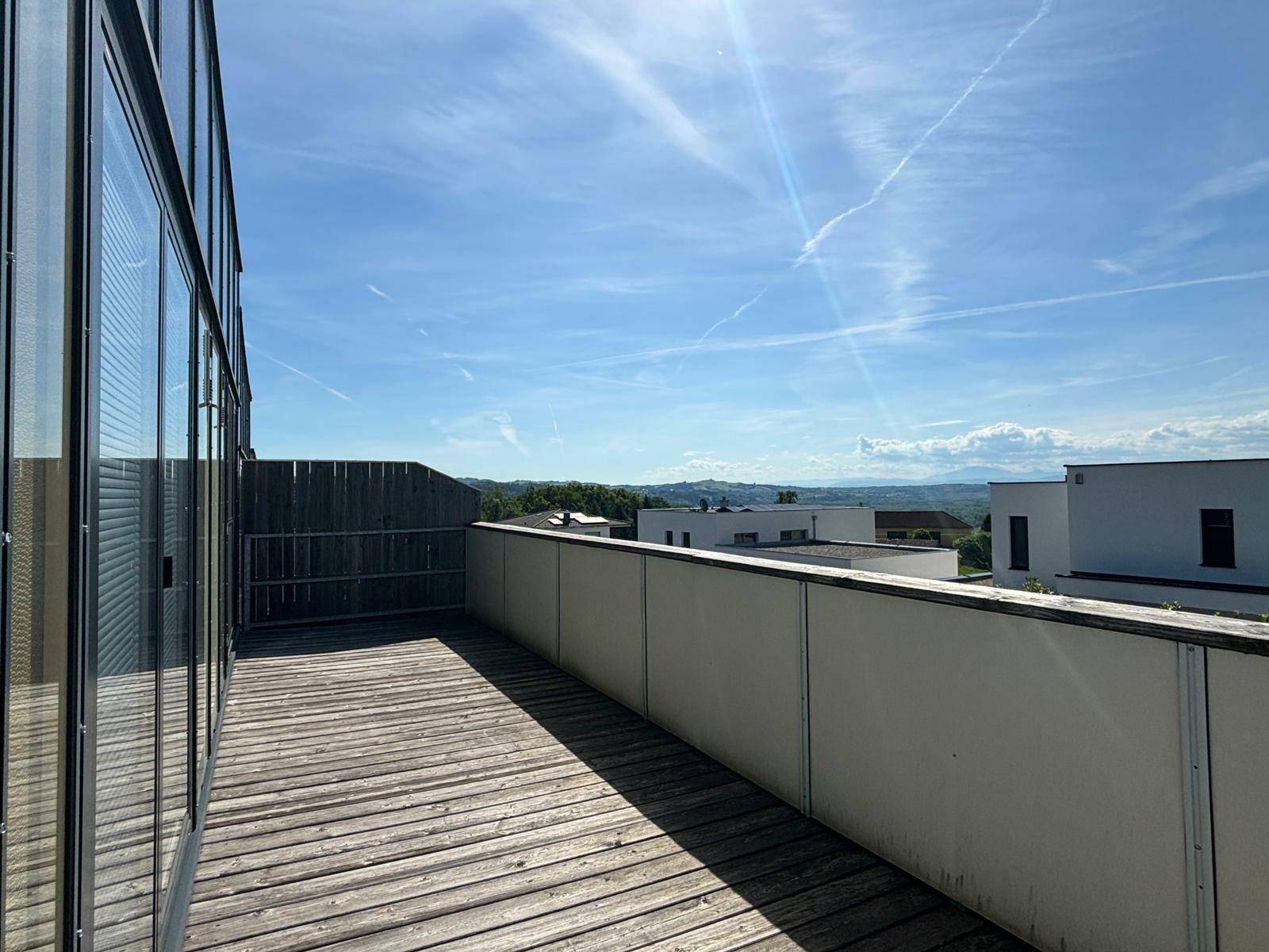 Geräumiger Balkon mit Holzboden und weitem Blick über die umliegende Landschaft.