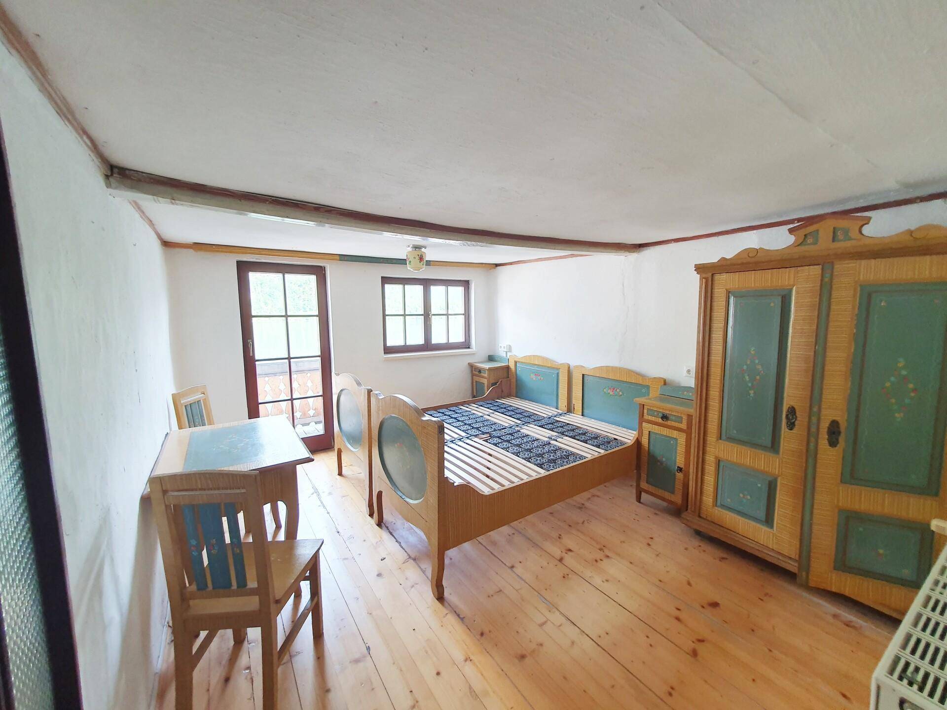 Gemütliches Schlafzimmer mit traditionellen, bemalten Holzmöbeln und Zugang zu einem Balkon.