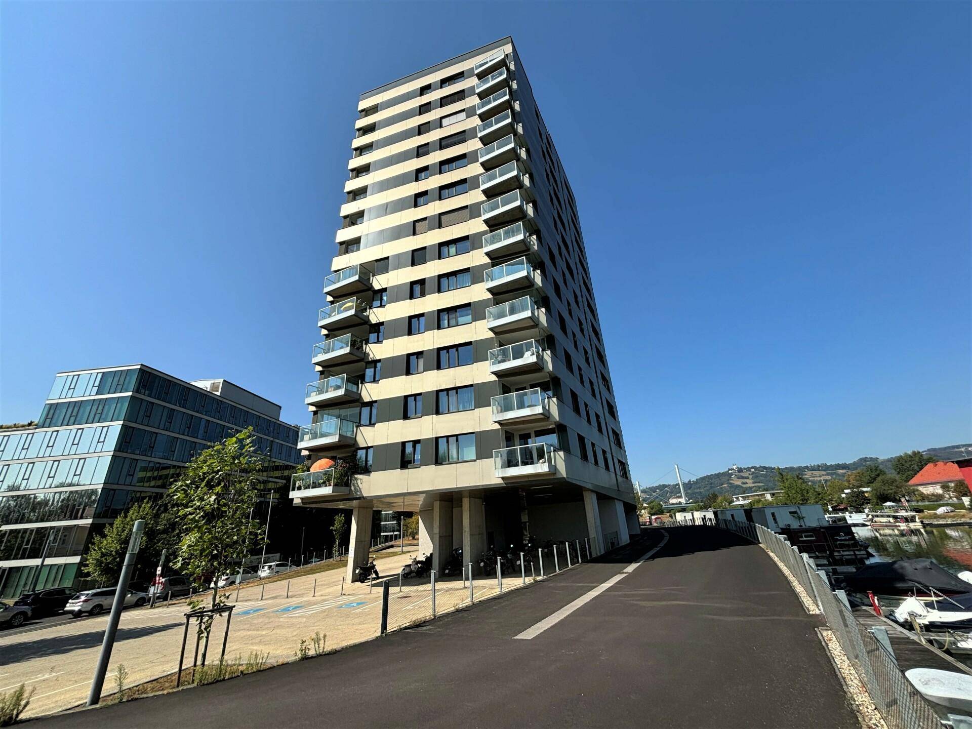 Modernes Hochhaus mit Balkonen und Glasfassade, direkt am Wasser gelegen.