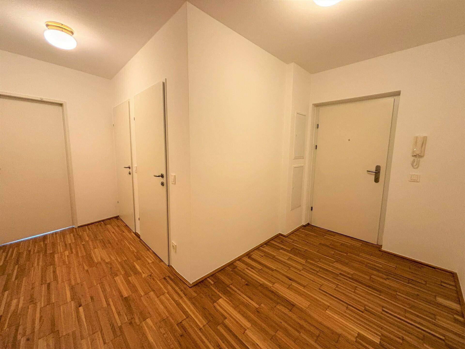 Heller Flur mit Holzboden und mehreren weißen Türen, die zu den angrenzenden Räumen führen.