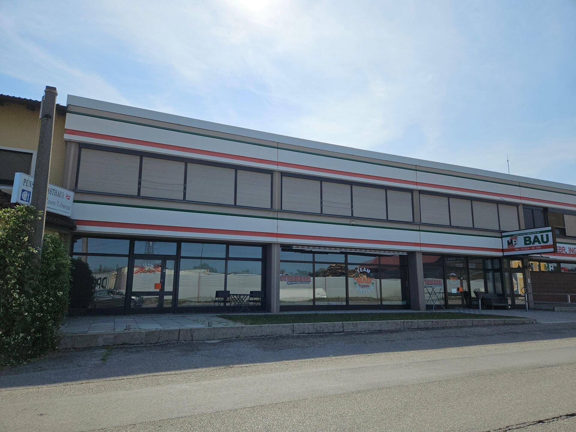 Modernes Geschäftsgebäude mit großen Schaufenstern und einer markanten gestreiften Fassade.
