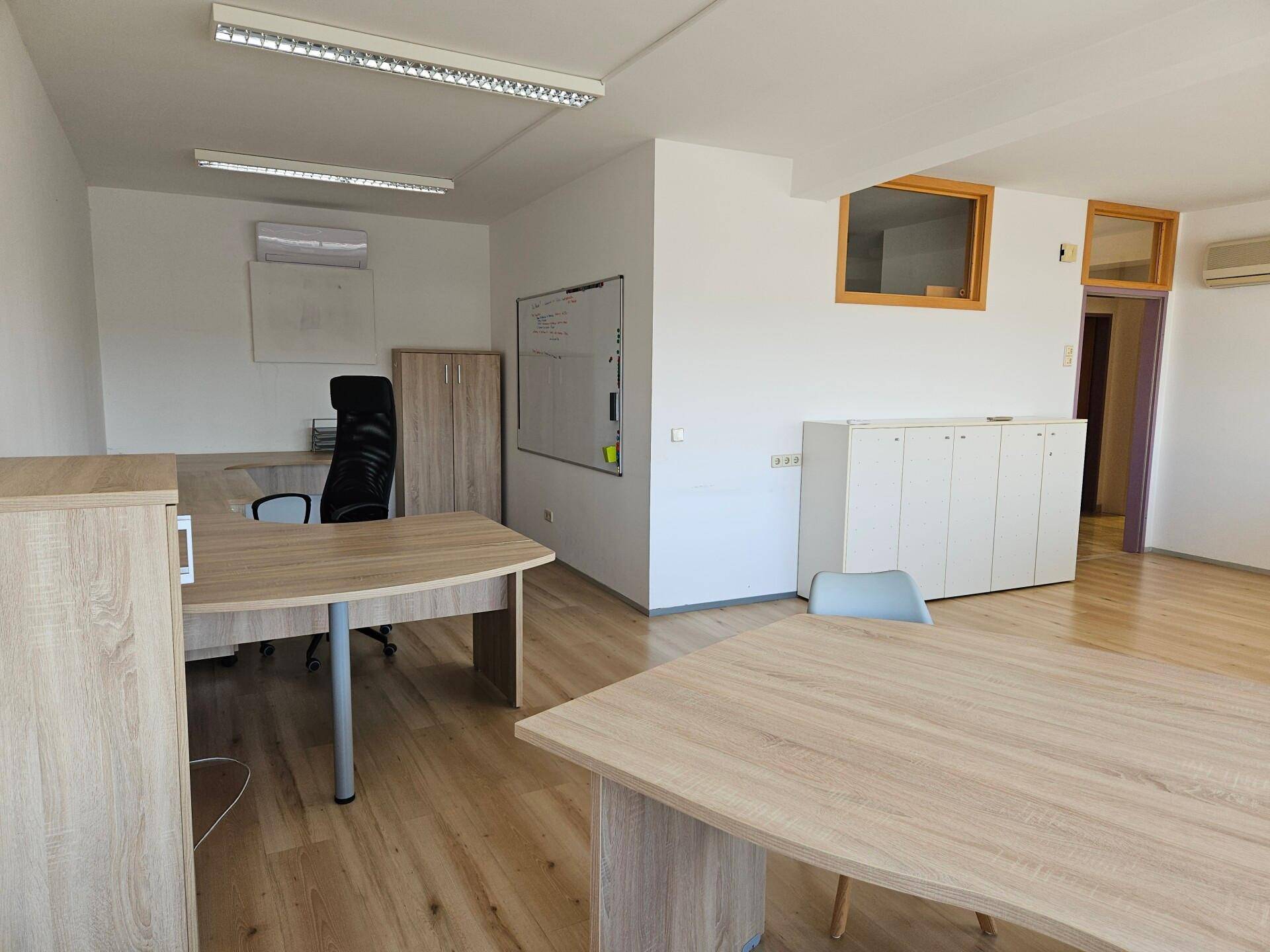 Funktionales Büro mit Whiteboards, Klimaanlage und mehreren Arbeitsbereichen für effizientes Arbeiten.