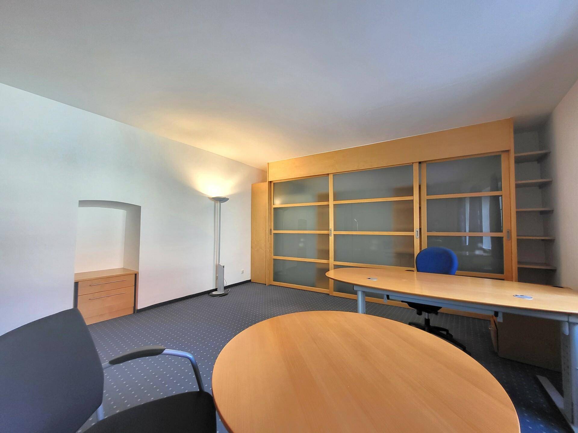 Büro mit Teppichboden, Schiebetüren aus Holz und Glas, sowie runden und ovalen Besprechungstischen.