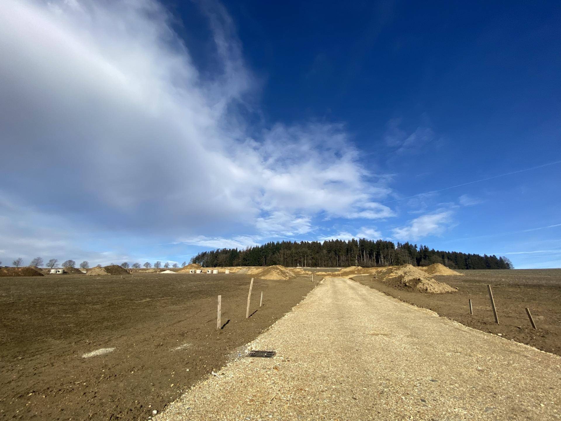 Unbebautes Grundstück mit Schotterweg und weitem Blick in die Landschaft.