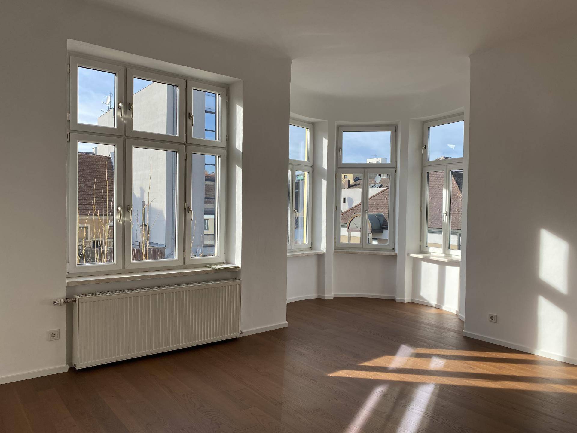 Heller Wohnbereich mit Erkerfenstern, Holzboden und viel natürlichem Licht.
