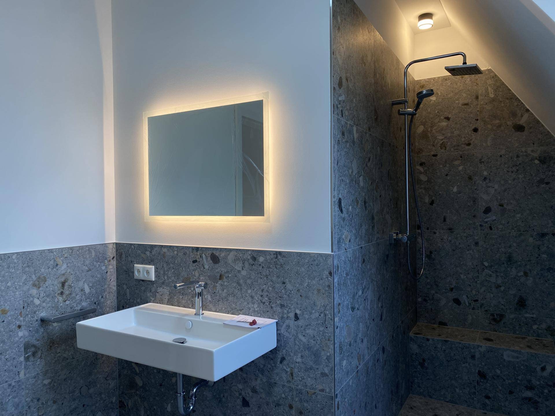 Modernes Badezimmer mit Regendusche, Einzelwaschbecken und stilvollen Fliesen.