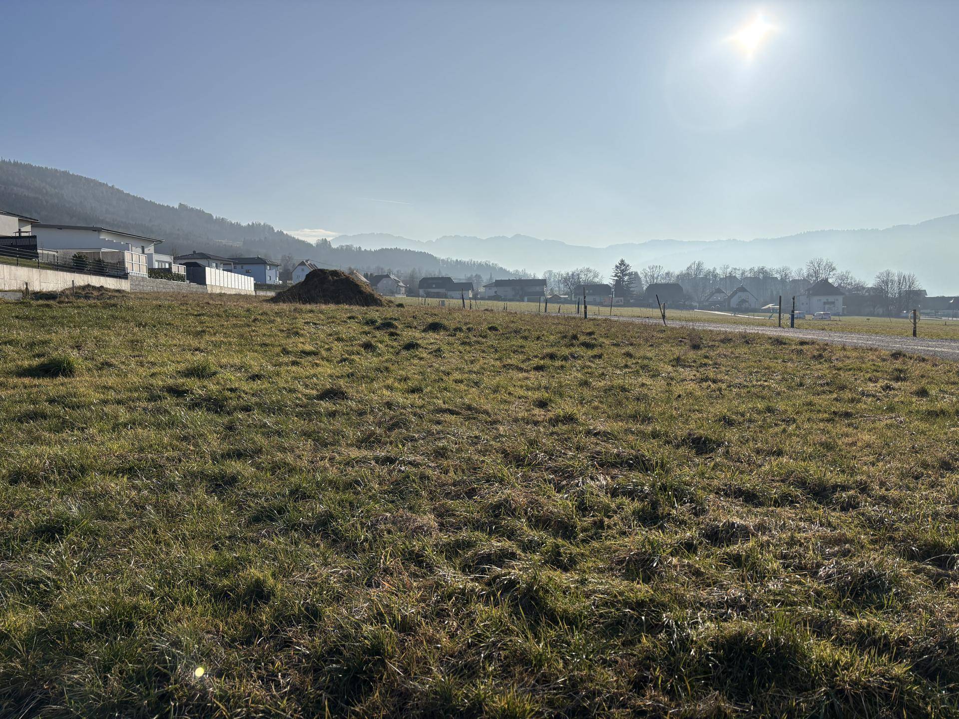 Sonniges Grundstück mit weitem Blick auf die hügelige Landschaft und die umliegenden Häuser.