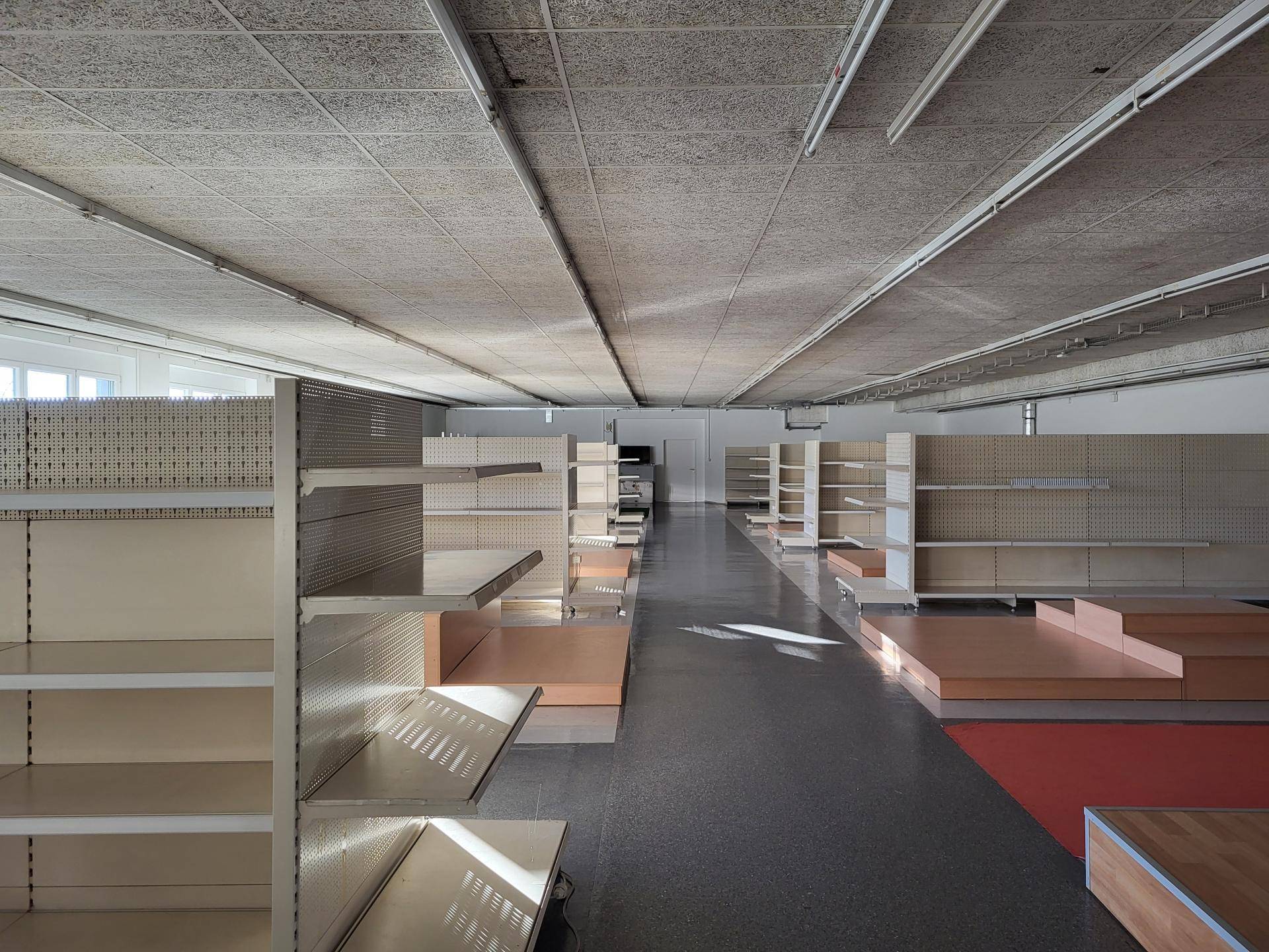 Großer, leerer Verkaufsraum mit modularen Regalsystemen und abgehängter Decke.