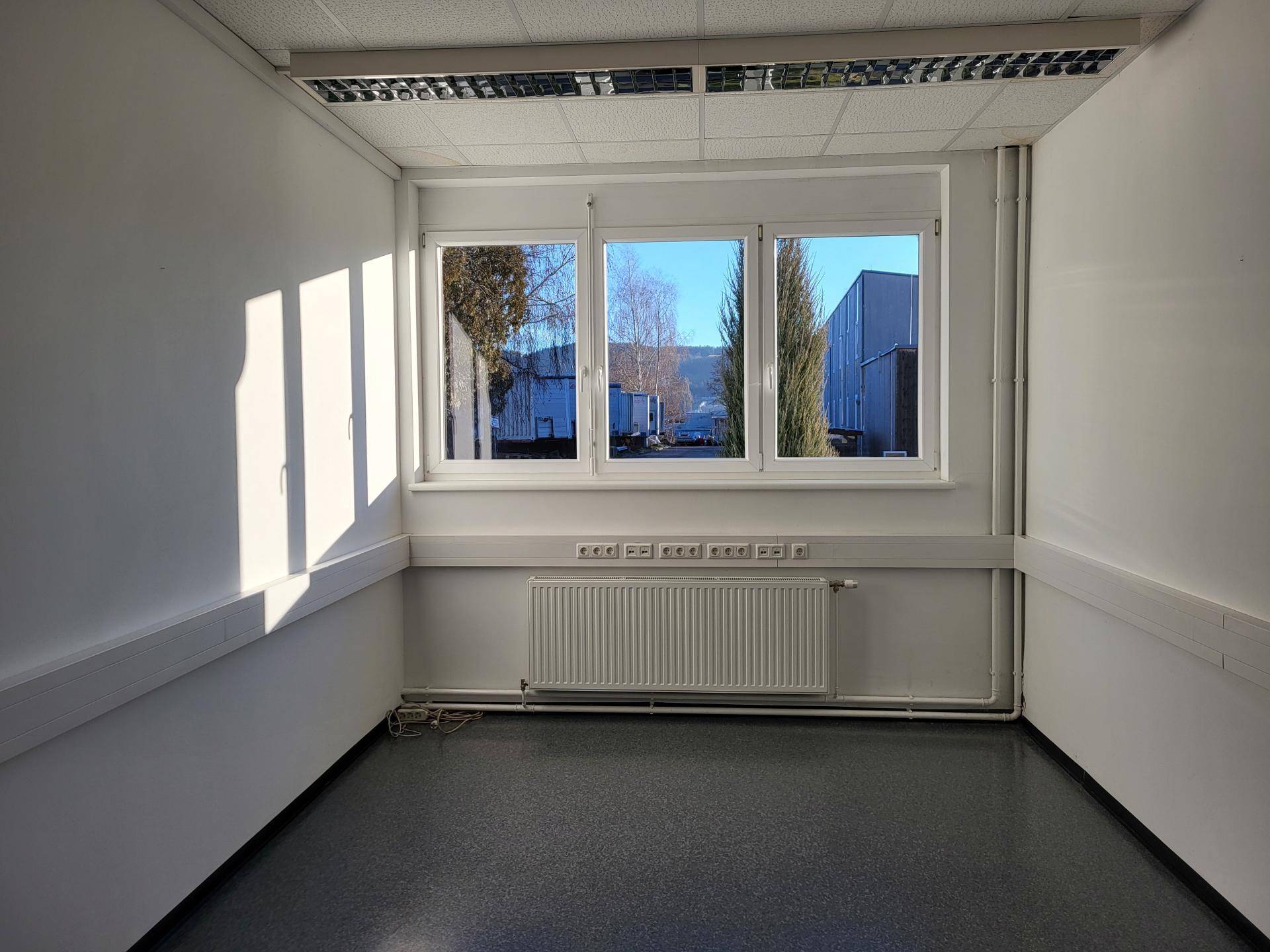 Kleiner, heller Raum mit großen Fenstern und Heizkörper, geeignet als Einzelbüro oder Abstellraum.
