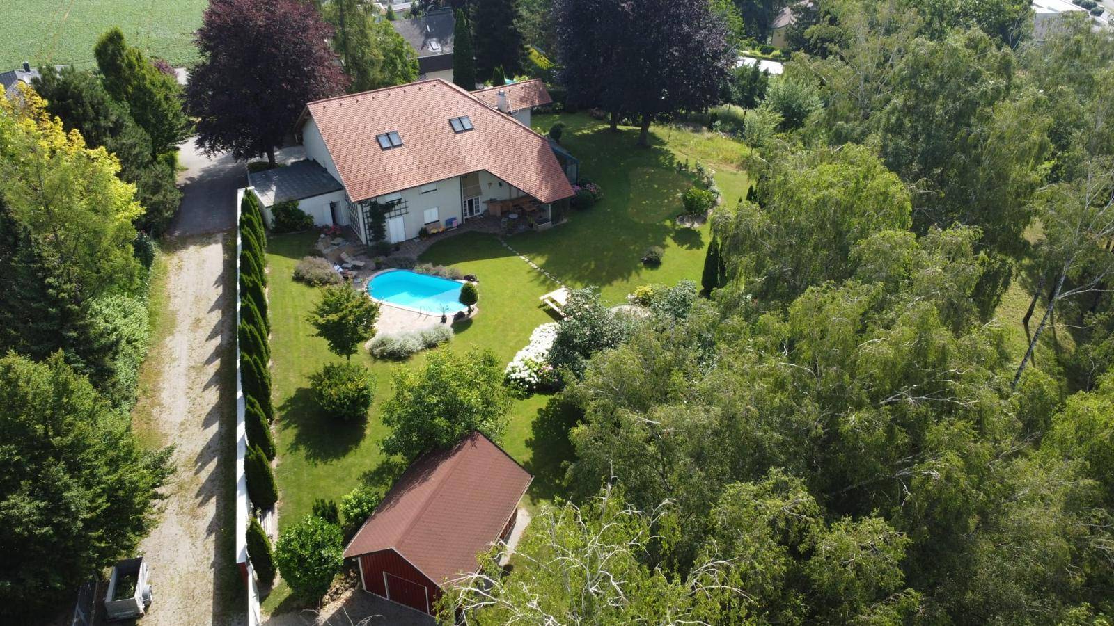 Luftaufnahme eines weitläufigen Anwesens mit Wohnhaus, Pool und großem Gartenbereich.