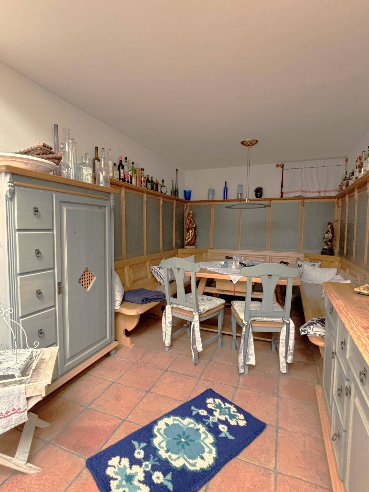 Traditioneller Essbereich mit Holztäfelung, eingebauten Bänken und Terrakotta-Fliesenboden.