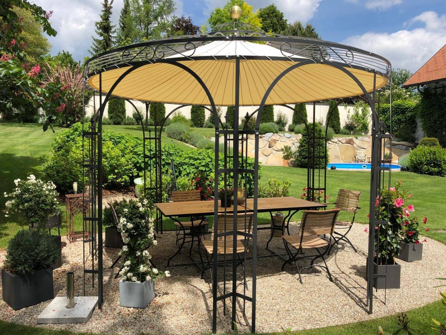 Eleganter Pavillon mit Esstisch und Stühlen in einem weitläufigen Garten mit kleinem Pool.