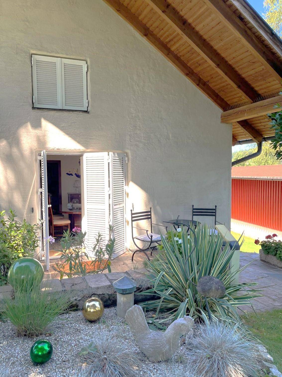 Kleine Terrasse am Haus mit Gartenblick und dekorativen Elementen im Vorgarten.
