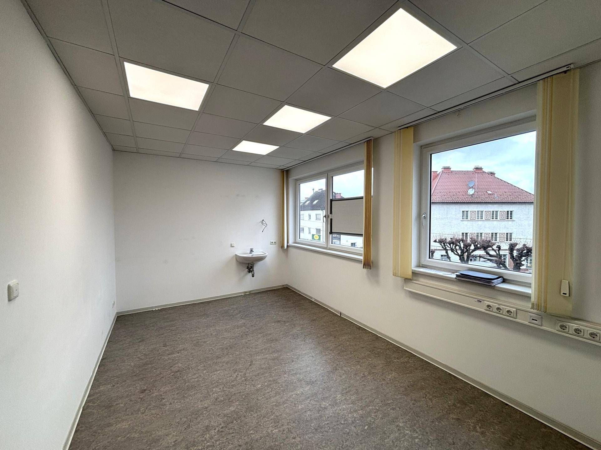 Helles Büro mit Waschbecken, großen Fenstern und einem pflegeleichten Linoleumboden.