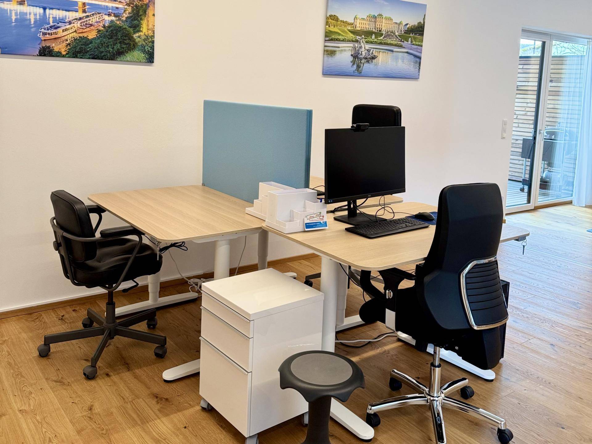 Heller und moderner Bürobereich mit mehreren Arbeitsplätzen, ergonomischen Stühlen und Holzboden.