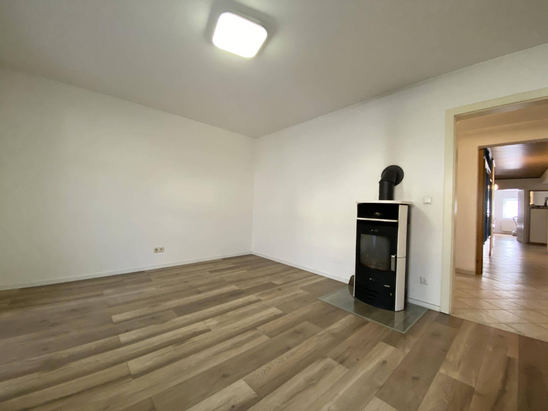 Gemütlicher Raum mit Holzboden und einem modernen Holzofen, der für Wärme sorgt.