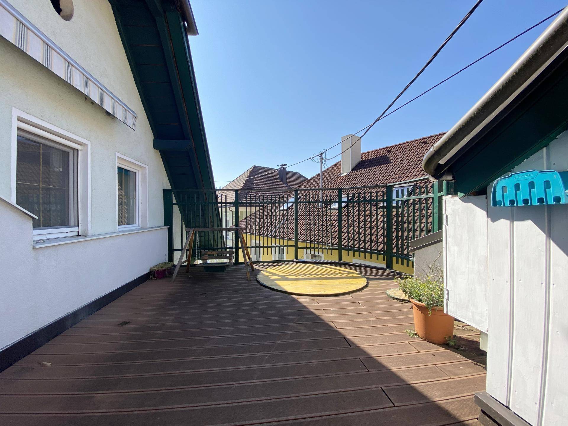 Geräumige Dachterrasse mit Holzboden und Metallgeländer, ideal für Entspannung im Freien.