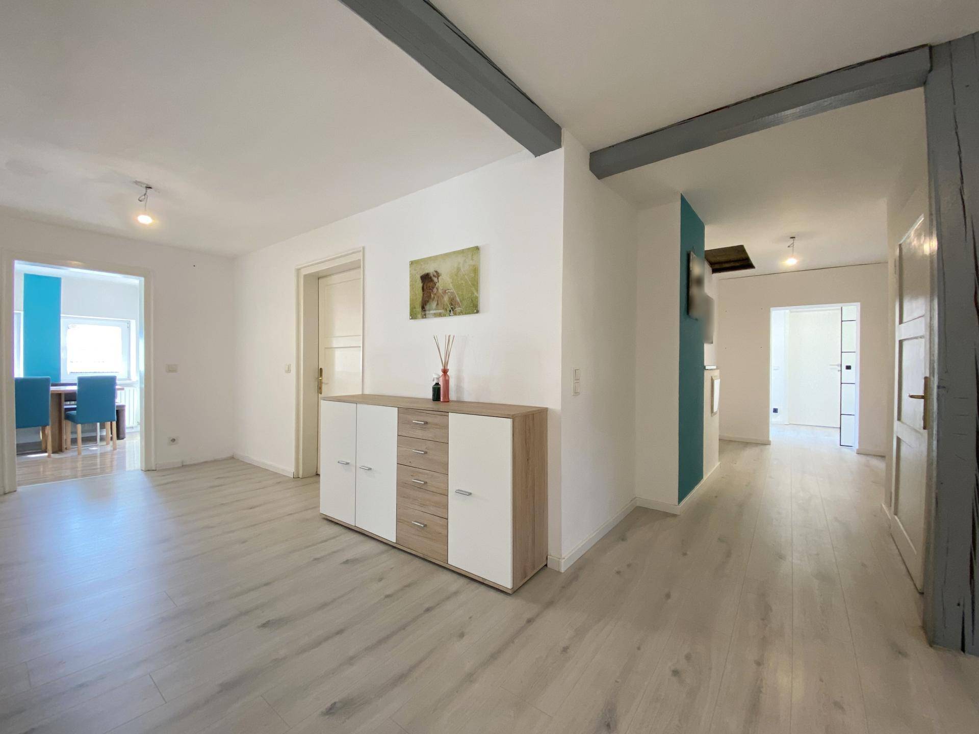 Heller Flur mit modernem Laminatboden und sichtbaren Holzbalken, die einen rustikalen Charme verleihen.