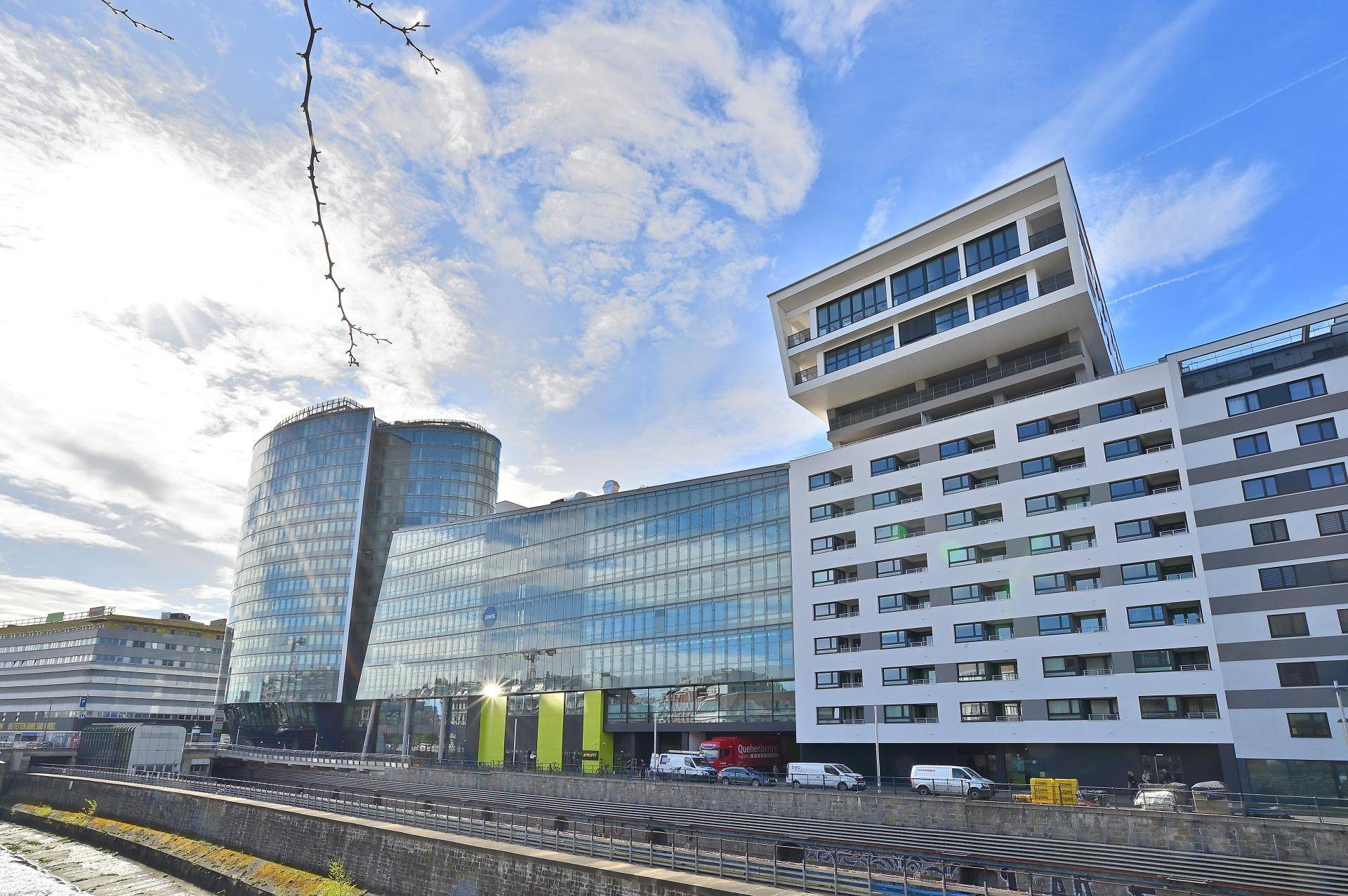 Moderne Architektur mit Glasfassade und markanten Gebäudeteilen unter blauem Himmel.