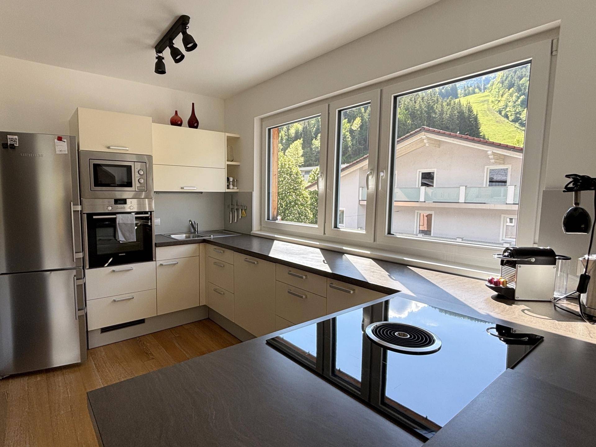 Helle Küche mit modernen Geräten, Induktionskochfeld und großem Fenster mit Bergblick.