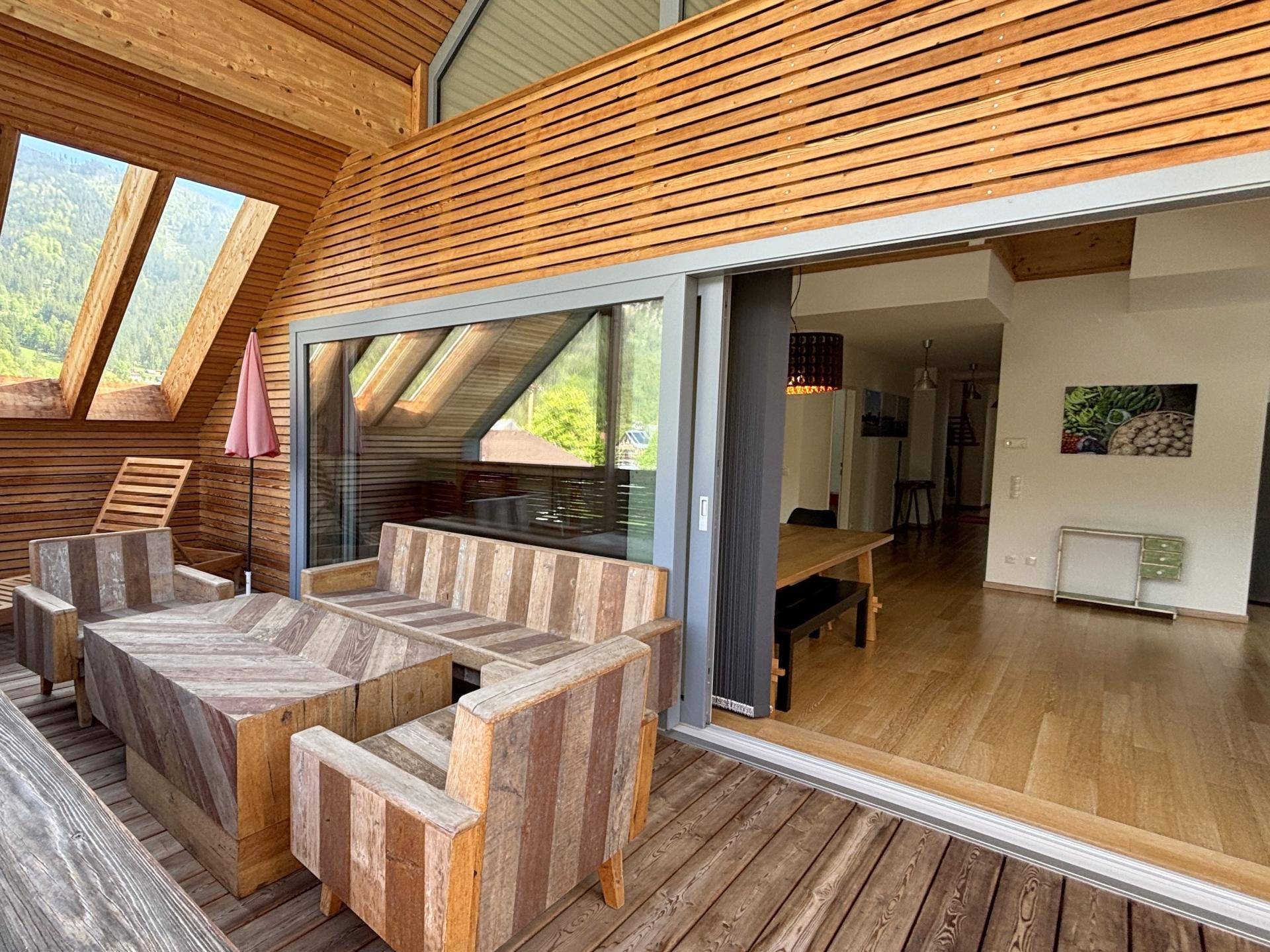 Holzterrasse mit Sitzgelegenheiten und Blick auf die umliegende Berglandschaft.